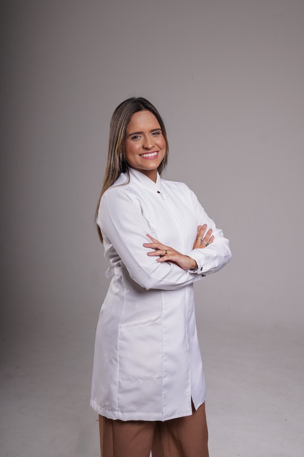 Rayssa Bezerra de jaleco branco, de braços cruzados e sorrindo